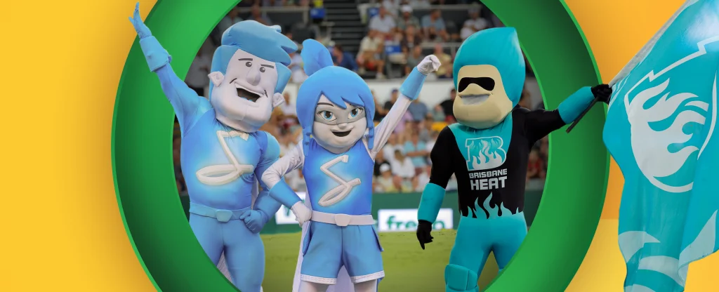 Adelaide Strikers mascots and Brisbane Heat mascot holding a flag at a stadium with spectators in the background framed within a green circle on a yellow background.